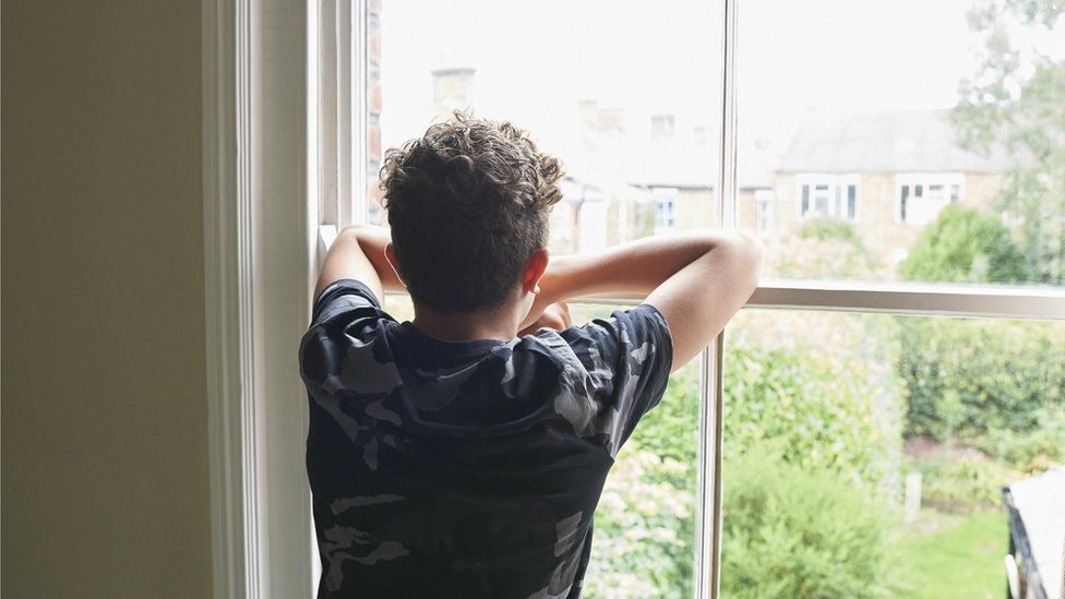 Teenage boy looking out of a window