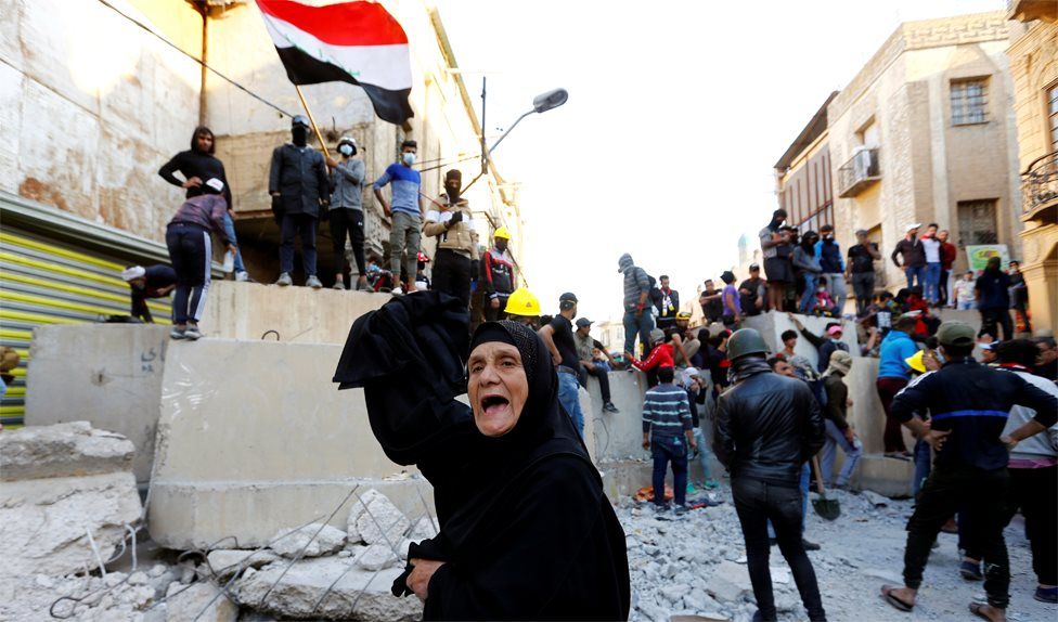 A woman shouts in front of anti-government protesters in Baghdad, Iraq (21 November 2019)