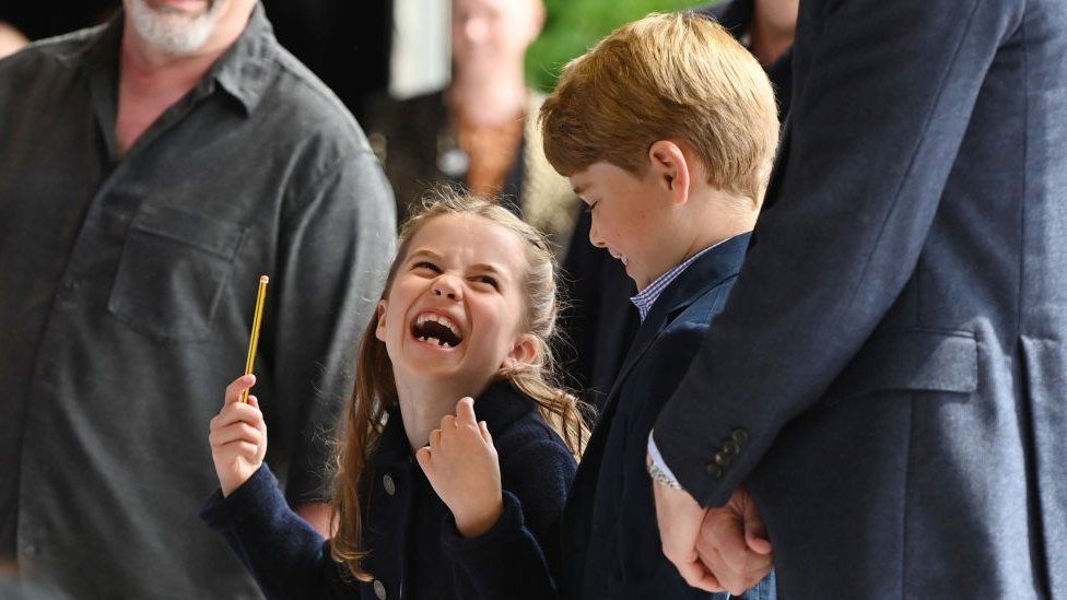 Princess Charlotte laughs as she conducts a band next to her brother Prince George
