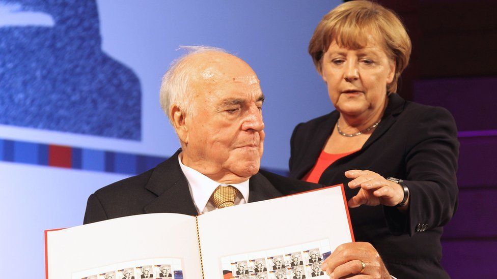 Former German Chancellor Helmut Kohl (L) and German Chancellor Angela Merkel (R) posing with stamps featuring him at the German Historical Museum