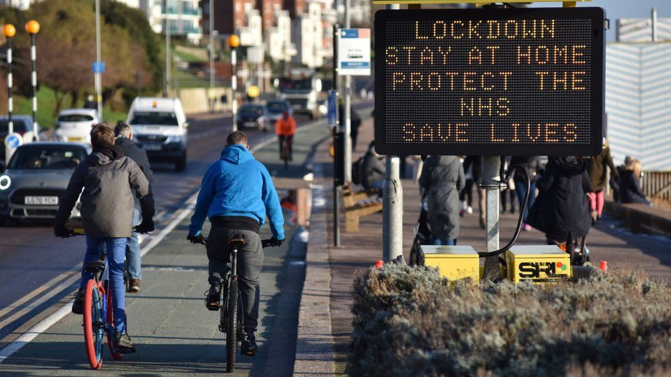 Cyclists ride past a digital public safety notice saying "Lockdown, Stay At Home, Protect The NHS, Save Lives" along the seafront at Westcliff, in Southend on 6 January