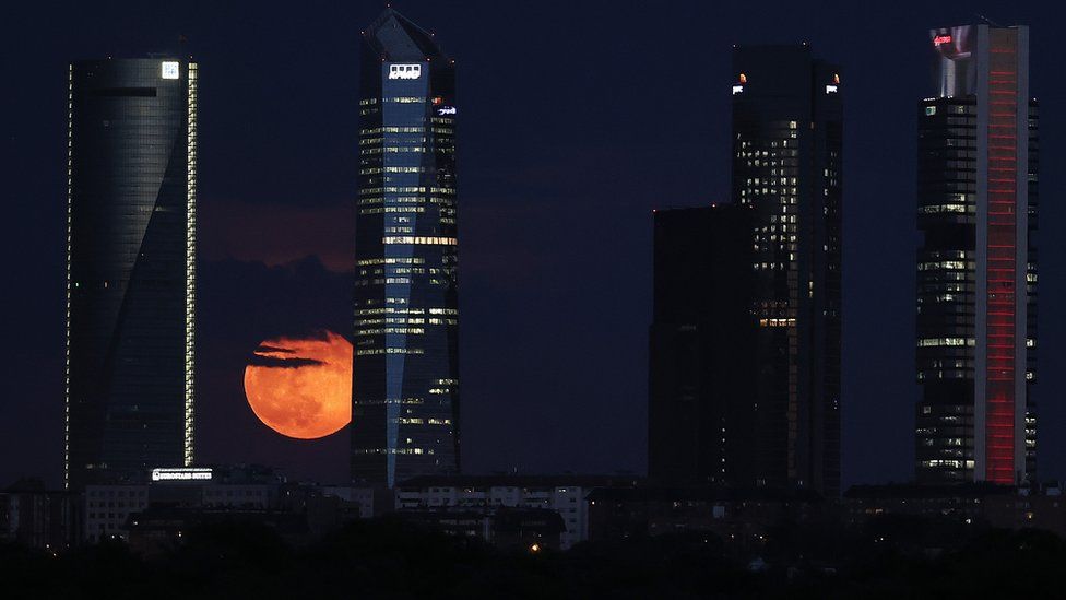 The Moon is seen rising behind skyscrapers in Madrid, Spain. Photo: 26 May 2021