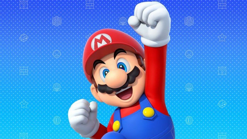 Mario fist pumping the air. Mario is an animation based on an Italian plumber, wearing a red hat and top with blue overalls. He wears white gloves and has blue eyes and a bushy brown moustache.