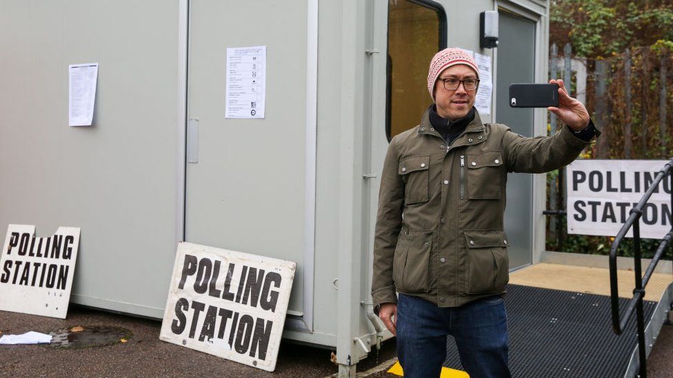 Мужчина делает селфи возле избирательного участка