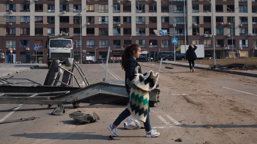 A woman walks past a residential area damaged by rocket strike on 23 March, 2022 in Kyiv, Ukraine