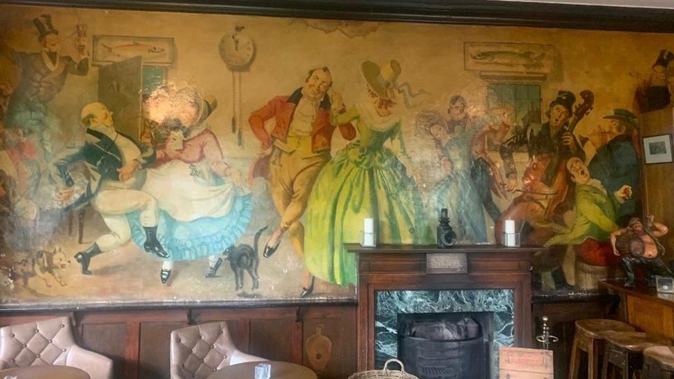 The section of mural depicting Dickensian caricatures around the bar