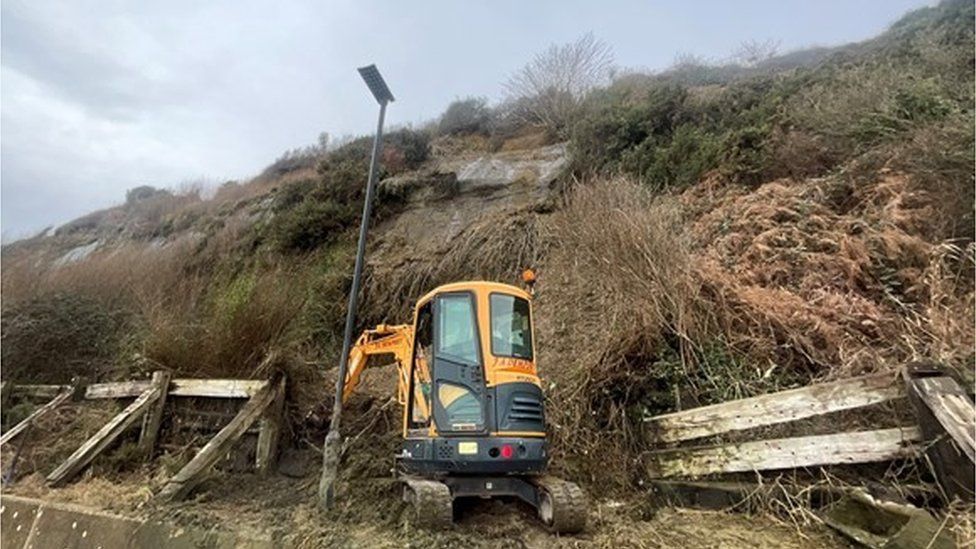 A small digger clearing a landslip