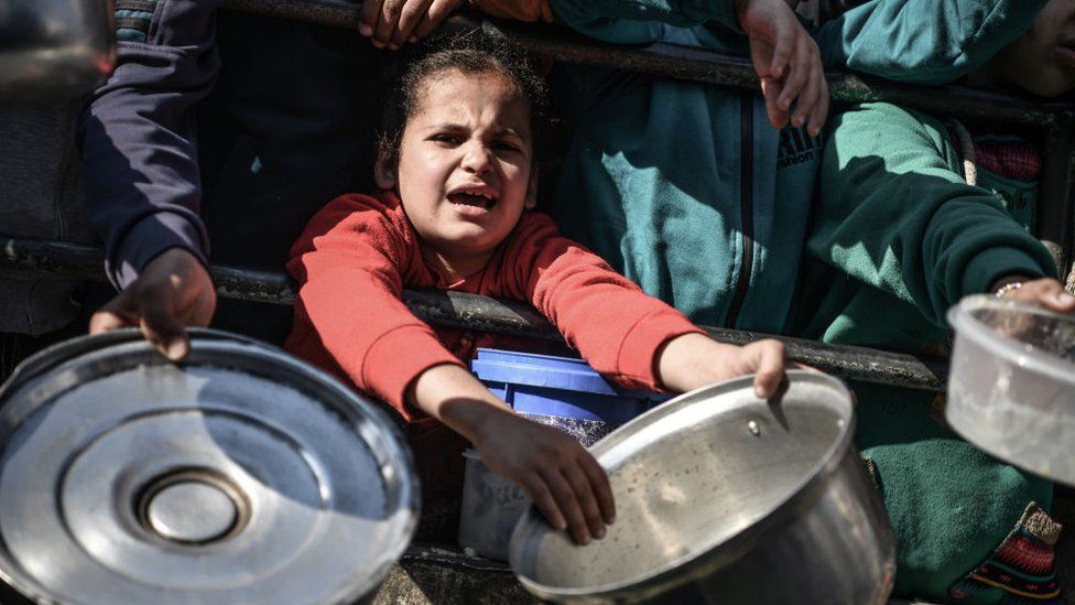 A Palestinian child queues to receive food