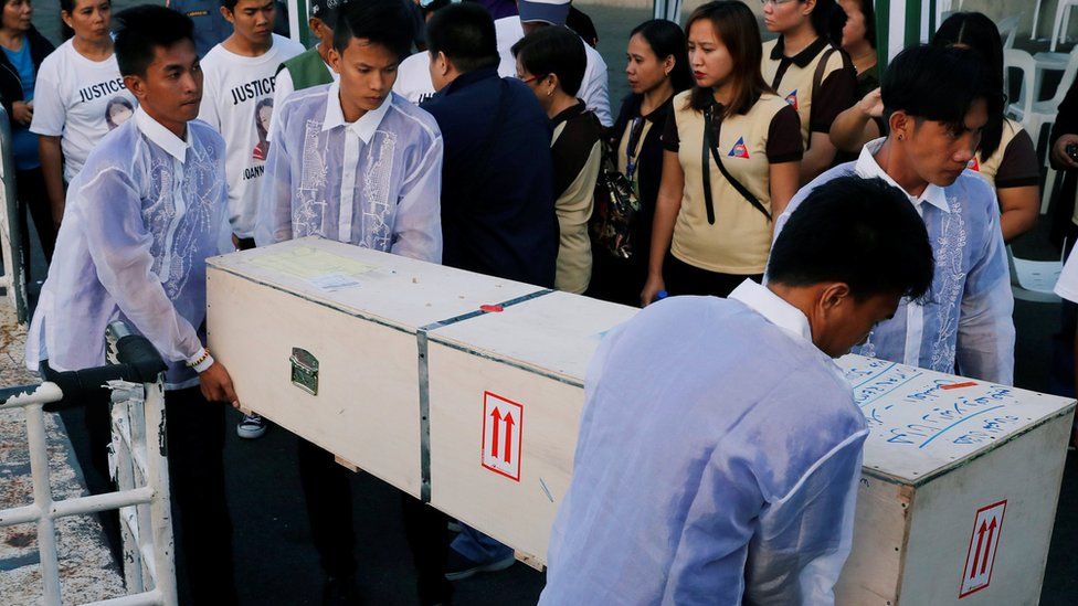Funeral workers carry a crate containing the body of Joanna Demafelis in her hometown in Iloilo province in the Philippines on 17 February 2018.