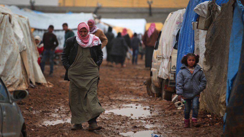 Syrian walk at a camp near the Bab al-Salam border crossing with Turkey, in Syria, Saturday, Feb. 6, 2016