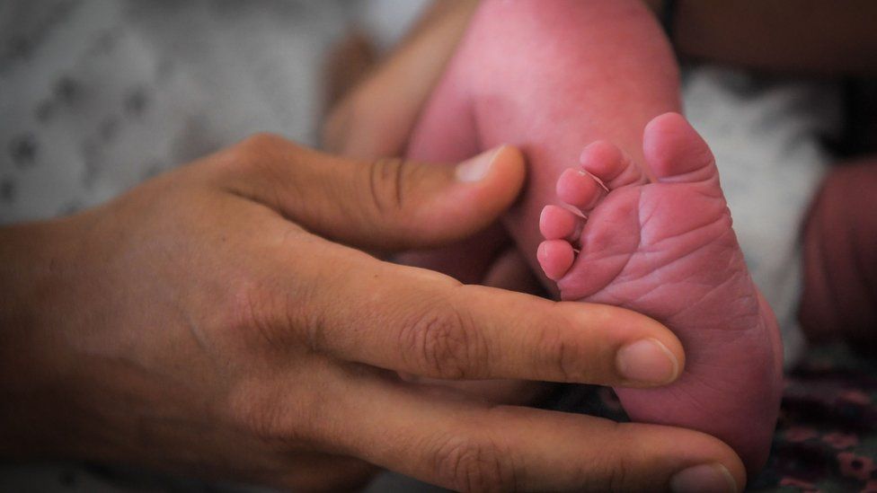 A mother holds her newborn baby's foot