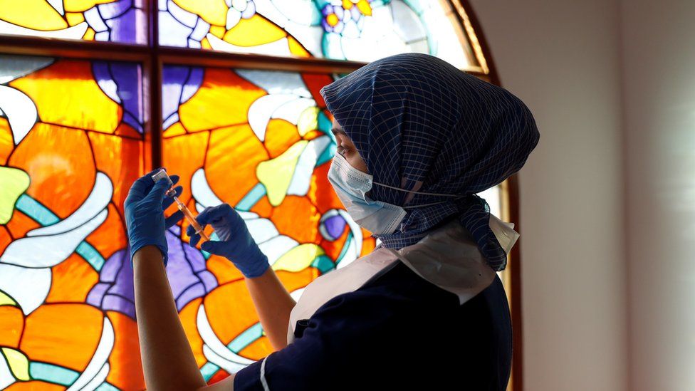 A woman prepares a dose of a coronavirus vaccine at Bradford Central Mosque