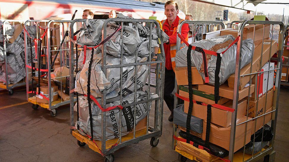 Royal Mail worker pushes a trolley of parcels