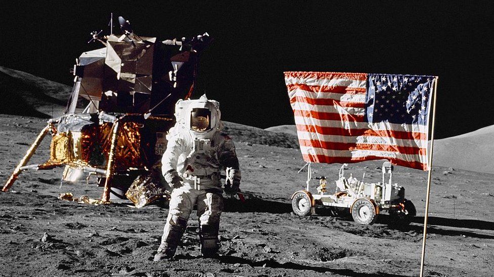 Харрисон Х. Шмитт, пилот лунного модуля, стоит на поверхности Луны рядом с флагом Соединенных Штатов во время последней миссии НАСА по высадке на Луну из серии «Аполлон», 13 декабря 1972 года.