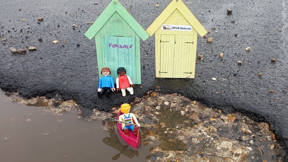 Toy beach huts at a pothole