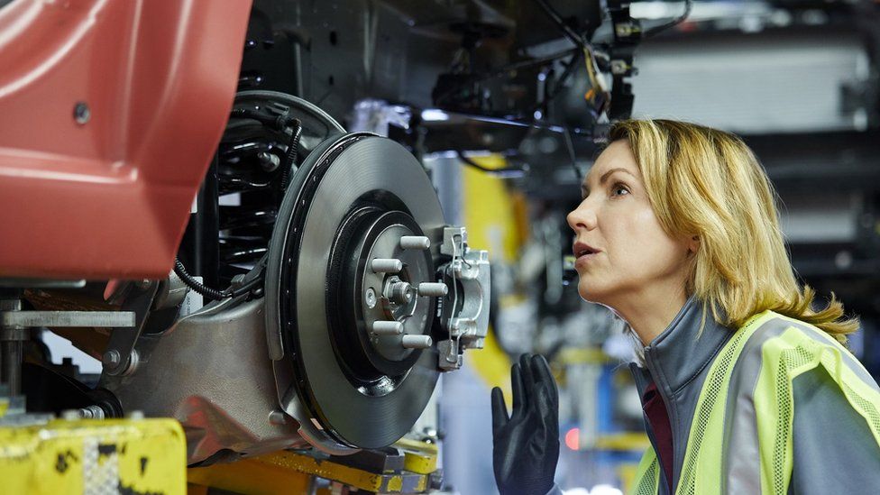 Female maintenance engineer examining car at factory