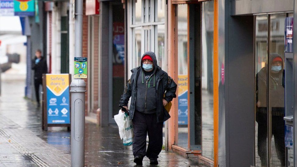 A man wears a face mask while walking through Bridgend town centre