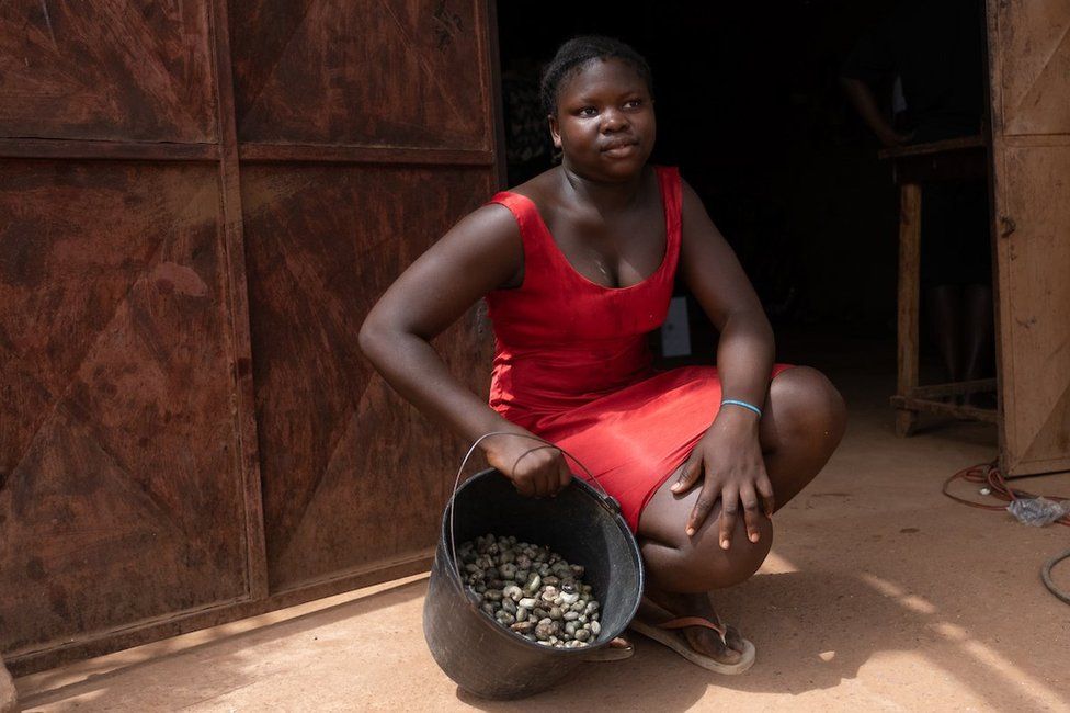 Alciony Fernandez, 14 years old, poses with her four kilos of cashews from her family farm she says she sells at 350 CFA per kilogram at a small store outside the capital, Bissau, has a scale that local cashew producers can use to weigh their crop. She walked about thirty minutes to the store to weigh the cashews.