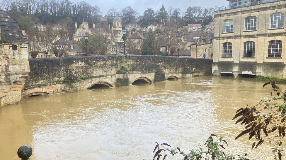 A high river in Bradford-on-Avon with buildings in the background