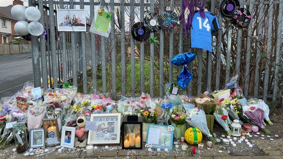 Floral tributes with candles and football t-shirts, balloons etc tied to railings