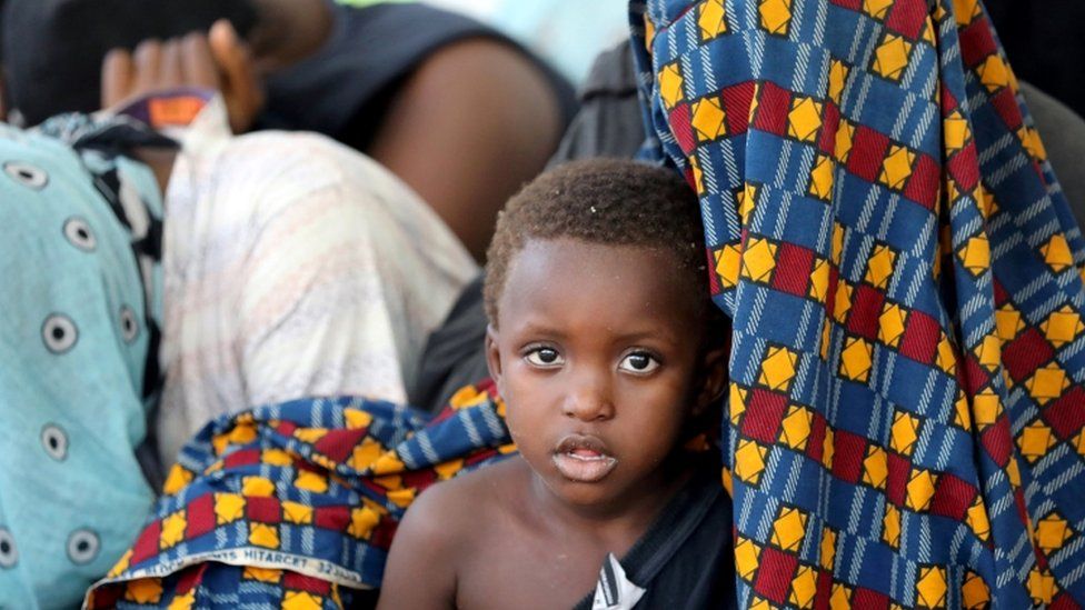 A migrant sits with his mother at a naval base after being rescued by Libyan coastguard
