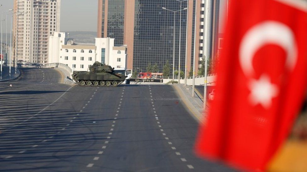 An abandoned tank is seen near a Turkish flag