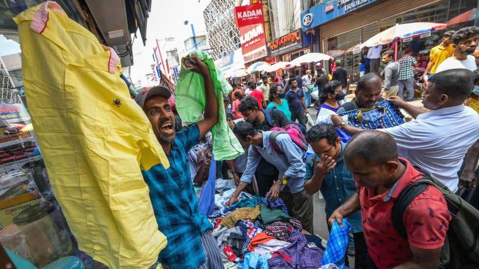 Покупатели из Шри-Ланки покупают одежду в киоске на рынке в Коломбо.