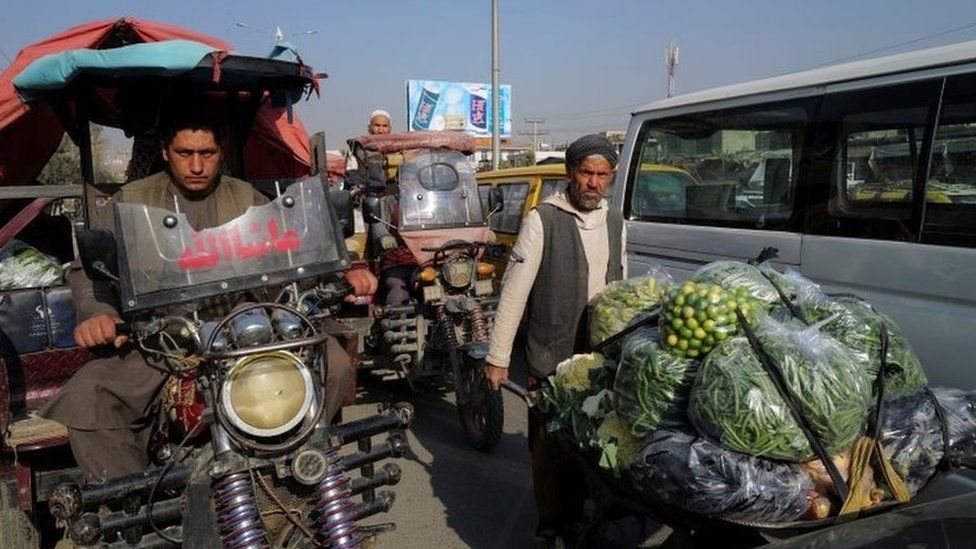 A man pushes wheelbarrow filled with vegetables and fruits at the market in Kabul, Afghanistan