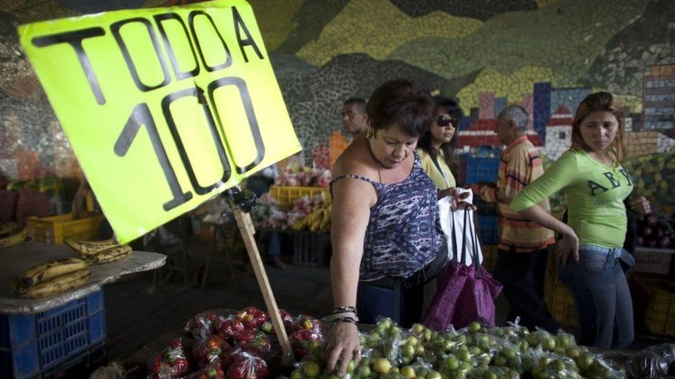 People buy vegetables on a street in Caracas (19 February 2016)