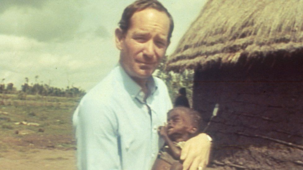 Michael Buerk holding a malnourished and starving child