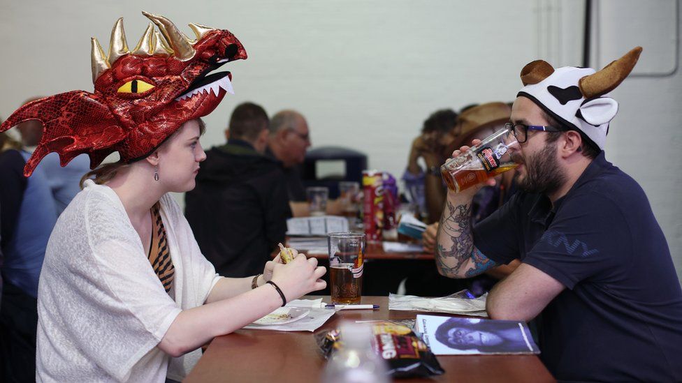 Friends sit down to drink a food during the traditional hat day during the CAMRA Great British Beer Festival at Olympia in London.