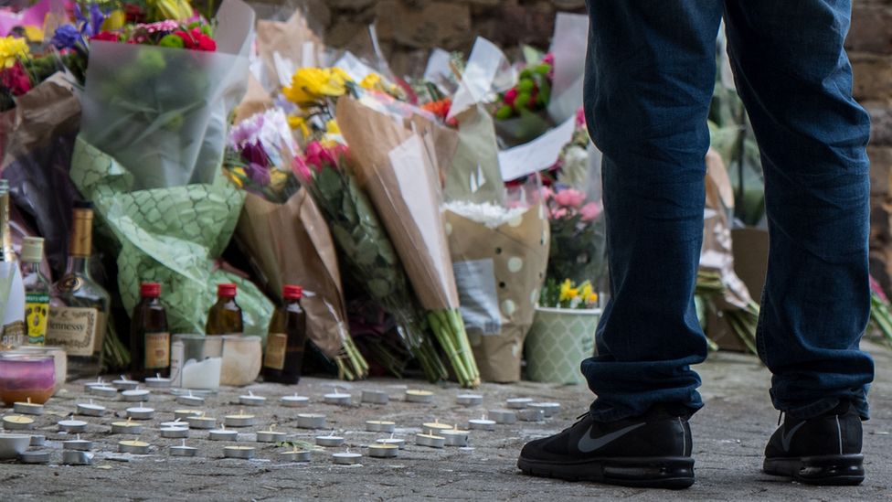 A man looks at floral tributes left at the scene in Hackney, London where Israel Ogunsola was stabbed to death in April 2018