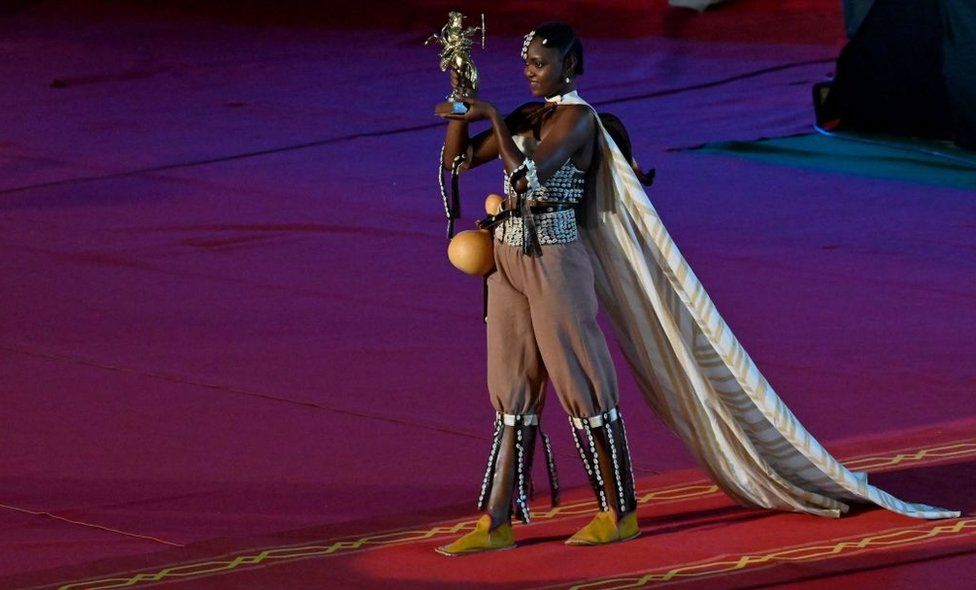 A woman holds the Yennenga Golden Stallion Trophy at the Palais des Sports in Ouagadougou.