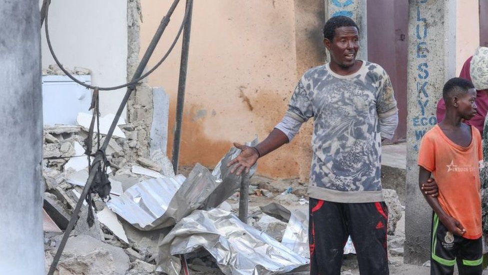 Жители остановились, чтобы оценить ущерб на месте нападения на отель «Палм-Бич» в Могадишо 10 июня.