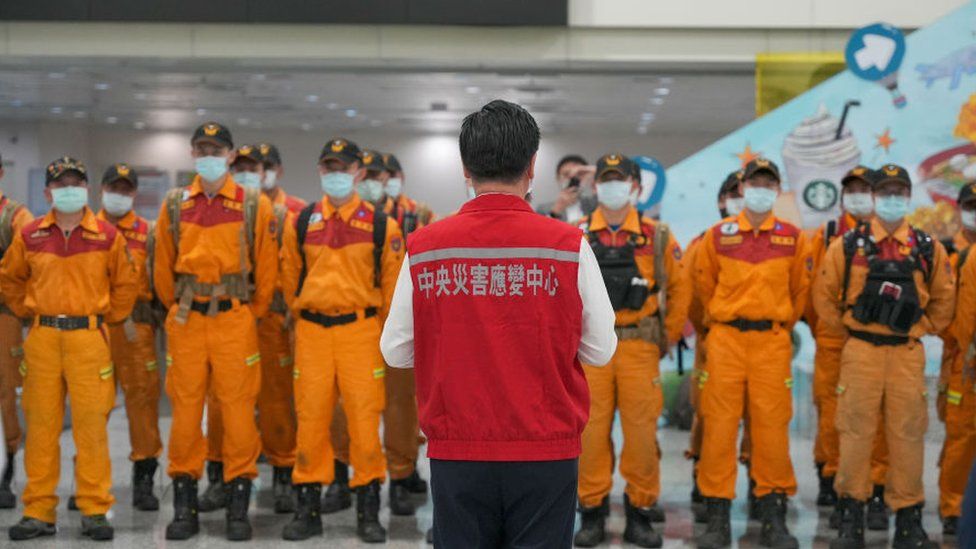 Тайваньский чиновник стоит перед группой спасателей