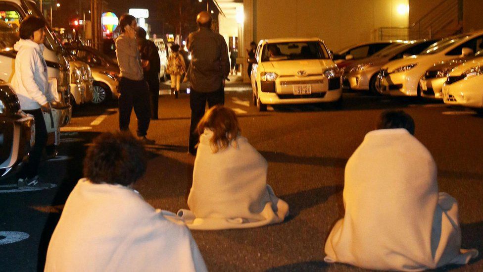 Stranded people wrap themselves in blankets outside a hotel after an earthquake in Kumamoto, southern Japan, Thursday, April 14, 2016
