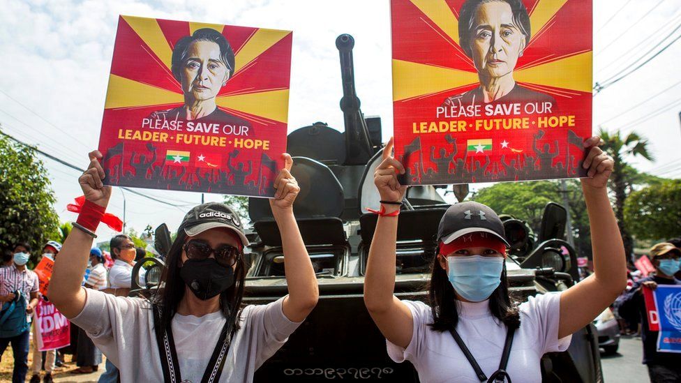 Демонстранты держат плакаты с изображением Аунг Сан Су Чжи во время акции протеста против военного переворота у Центрального банка Мьянмы в Янгоне, 15 февраля 2021 г.