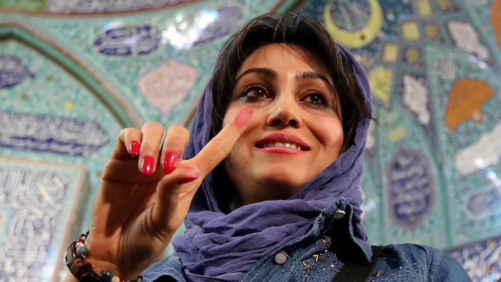 An Iranian woman displays her ink-stained finger after casting her ballot for both parliamentary elections and the Assembly of Experts at a polling station in Tehran, Iran