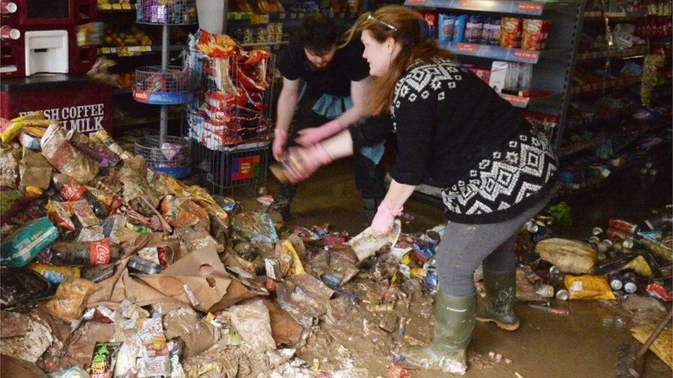 Shop workers in Cockermouth clean up flood damage