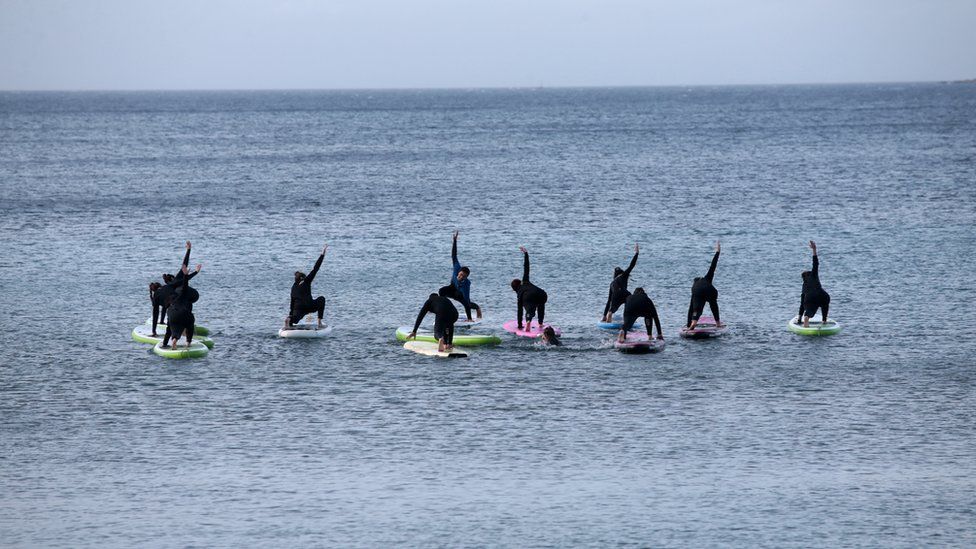 People exercise on paddle boards in the sea at a beach near Athens
