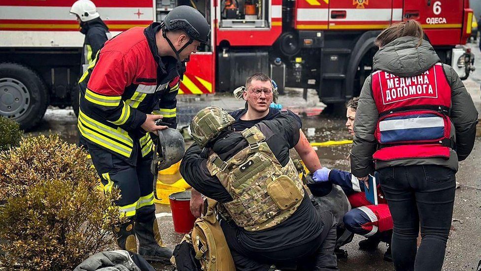 Rescuers help an injured man at the site of a Russian missile strike in Odesa