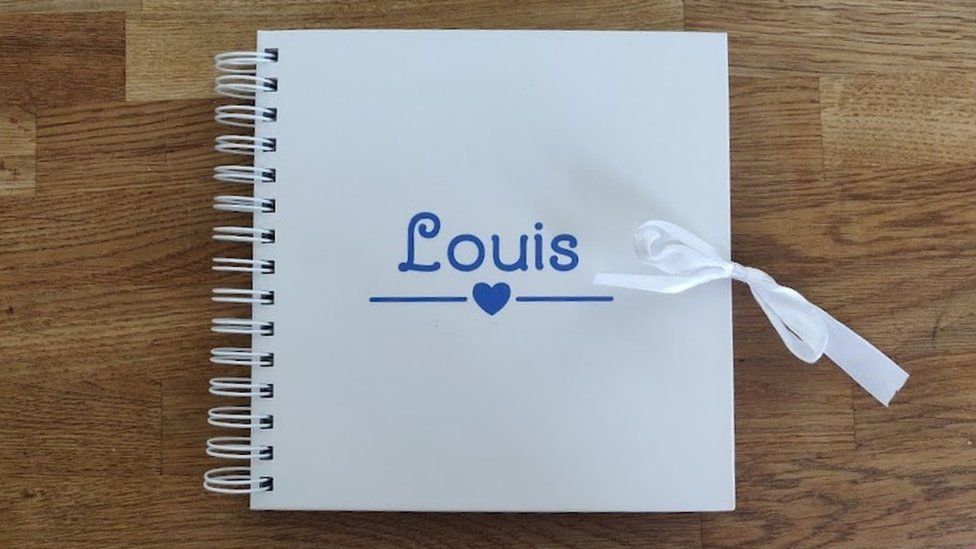 A white spiral photo album with the name written on it in blue writing