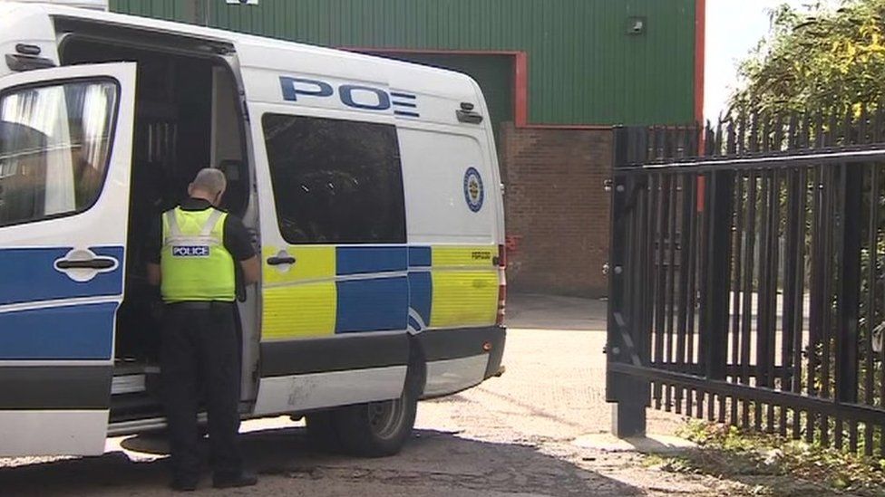 Police officer and van at entrance to industrial estate