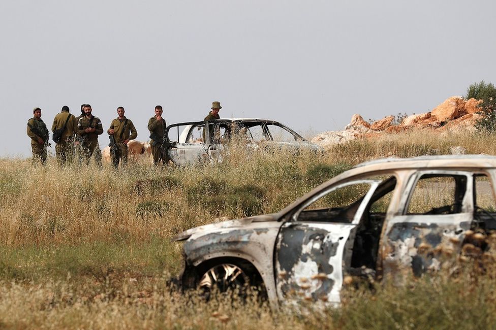 Soldiers inspect cars burned by Israeli settlers in the West Bank village Al-Mughayyir on 26 May 2023