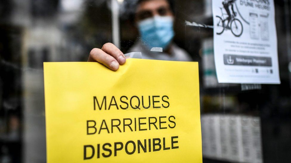 A pharmacist in France puts up a sign reading 'protective facemasks are available'
