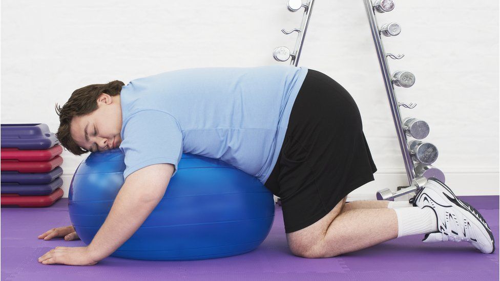 Fat man resting on exercise ball
