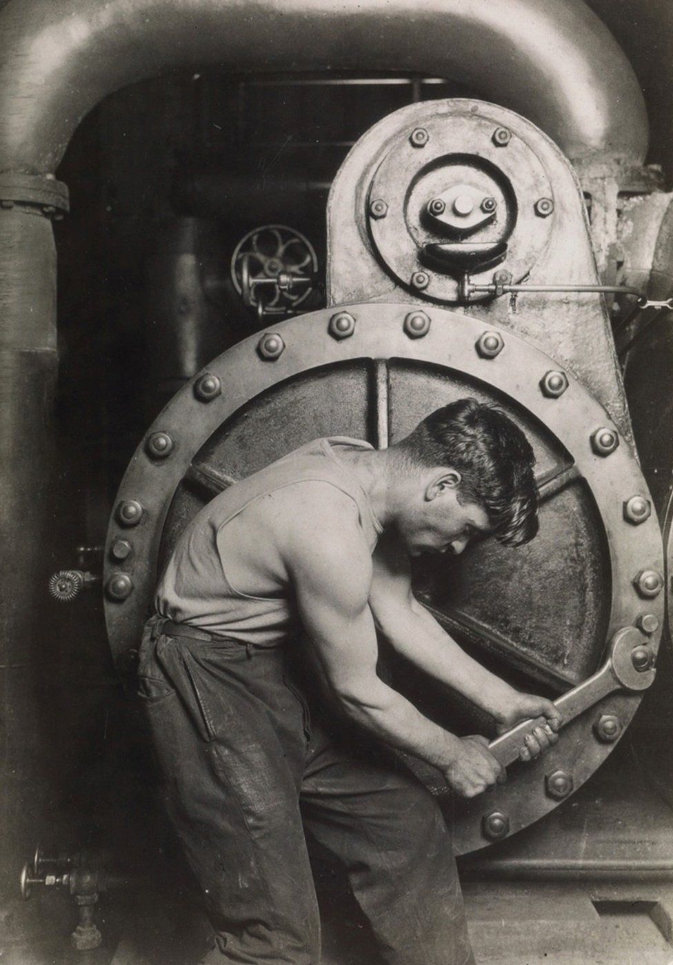 A mechanic uses a spanner on a steam pump.