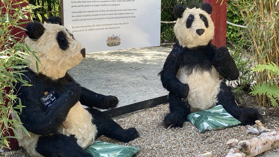 Two panda sculptures in front of a sign