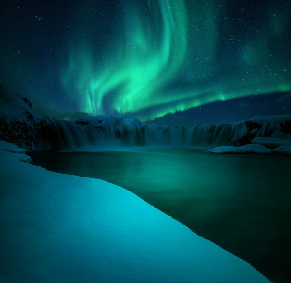 The northern lights over a waterfall