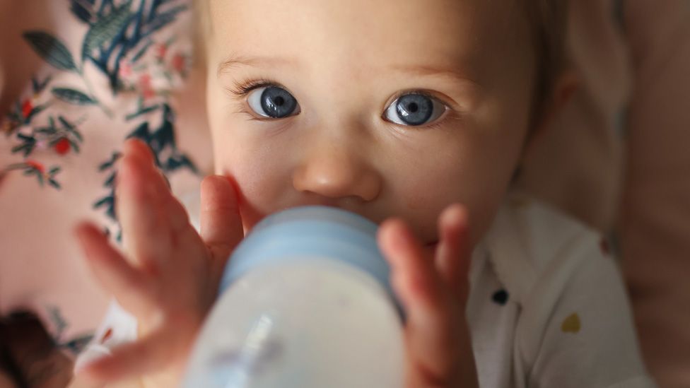 One year old baby girl drinking from a bottle